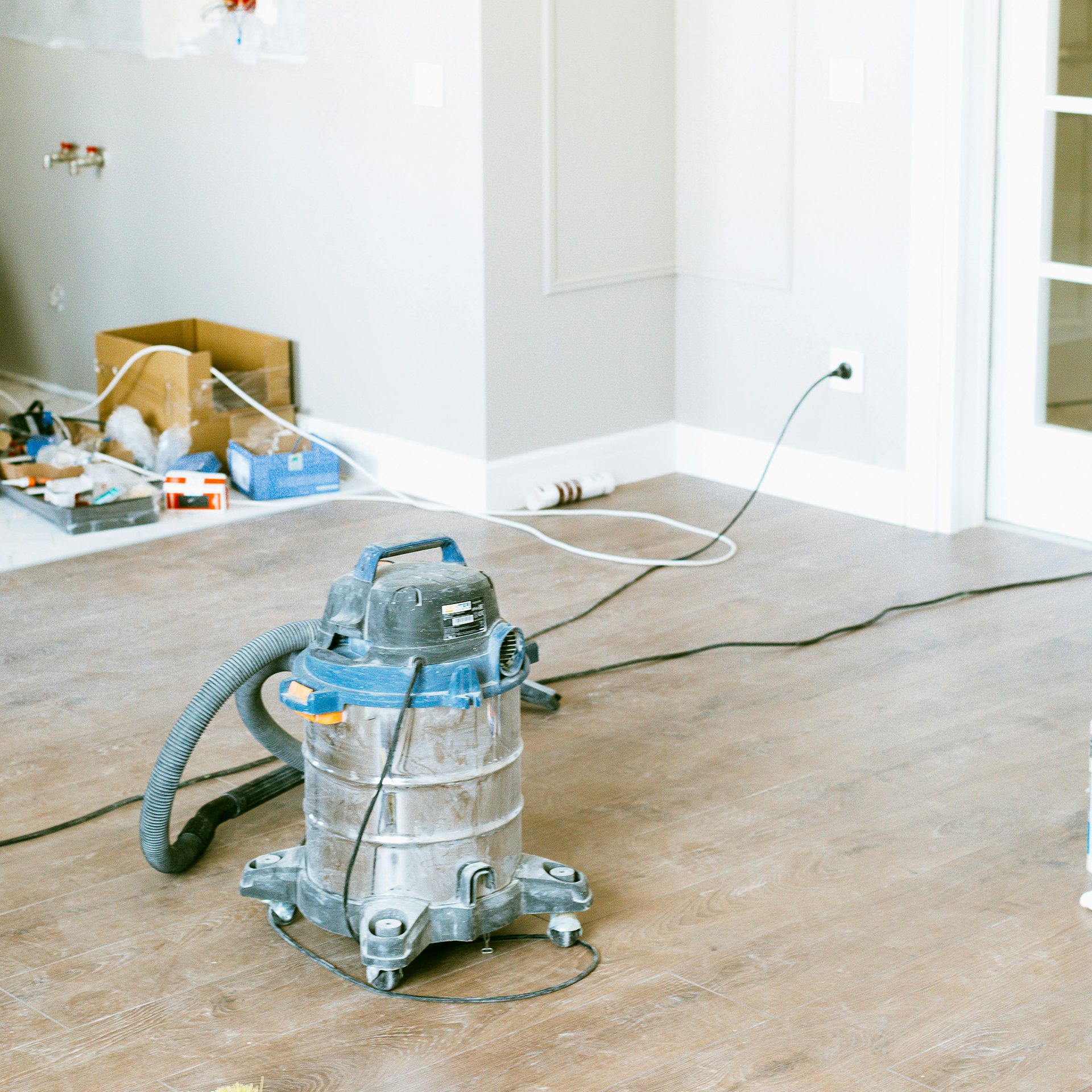 A vacuum cleaner is in action, effectively removing dirt from a hardwood floor after construction work